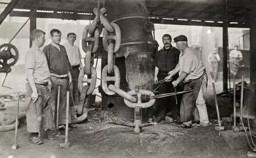 Historical photograph of metalworkers forging anchor chain links at Netherton forge in 1910