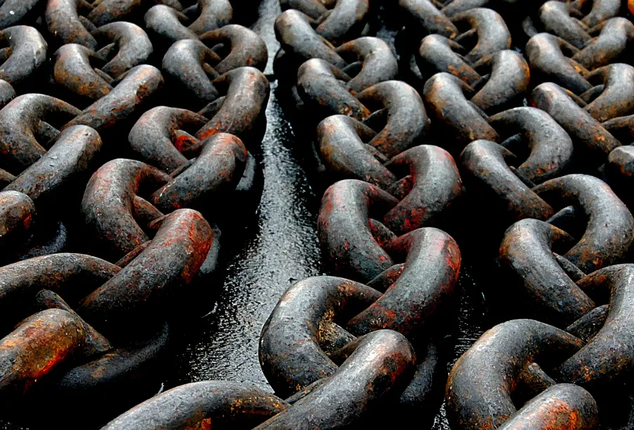 Large anchor chain cable coiled on a surface showing the scale and industrial construction