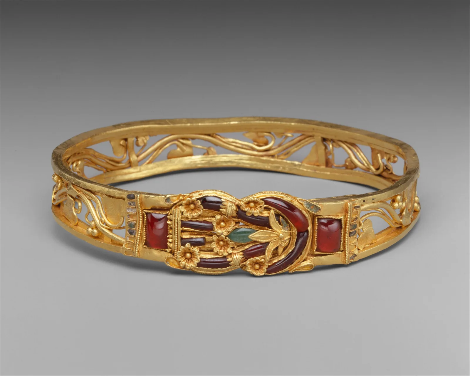 Brazalete helenístico de oro con un nudo de Hércules en el centro, incrustado con granates y esmalte