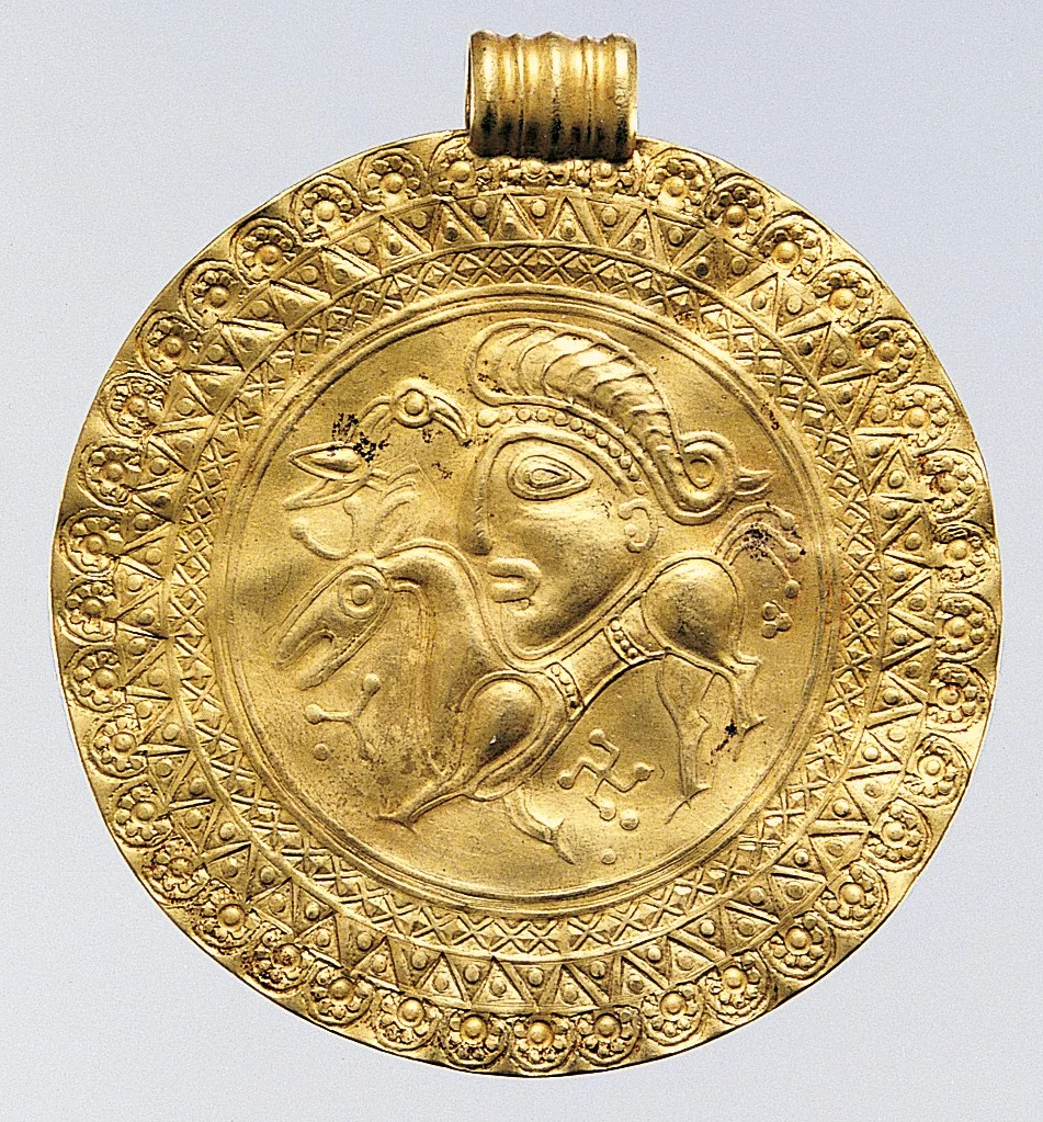 Scandinavian gold bracteate, a thin round pendant with stamped ornament, 400 to 600 AD