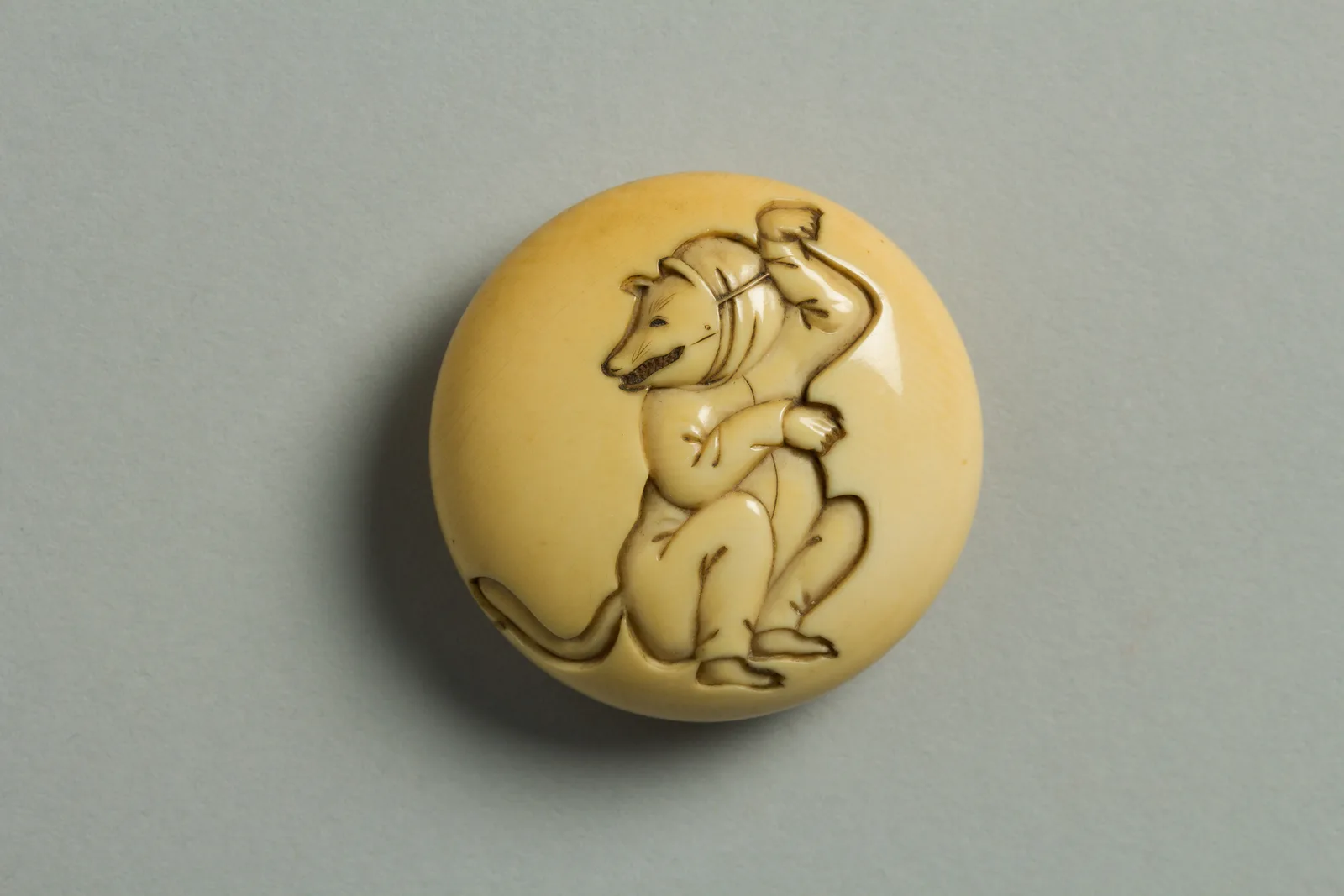 Netsuke circolare in avorio con un attore vestito da volpe