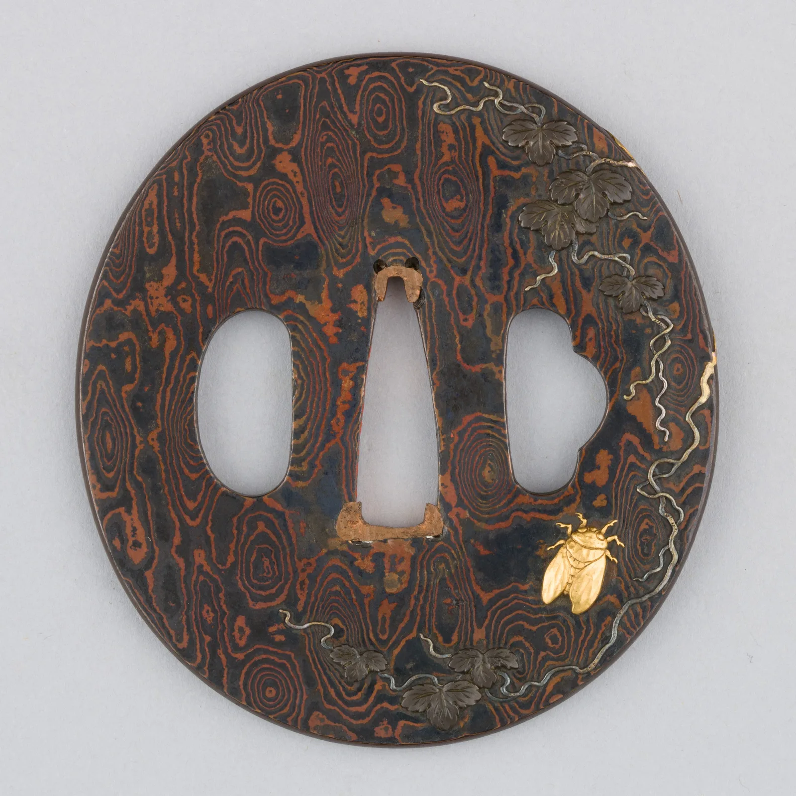 Tsuba aus Shakudo und Kupfer in Mokume-gane-Technik mit schwarzer Patina und goldenen Details