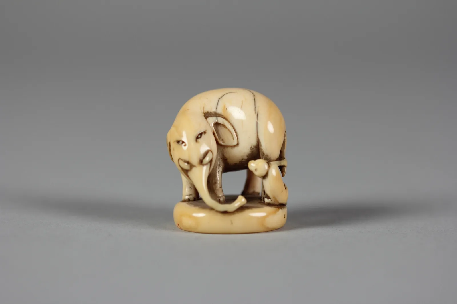 Netsuke japonês de marfim do século XIX: um elefante com um macaco sentado junto às patas