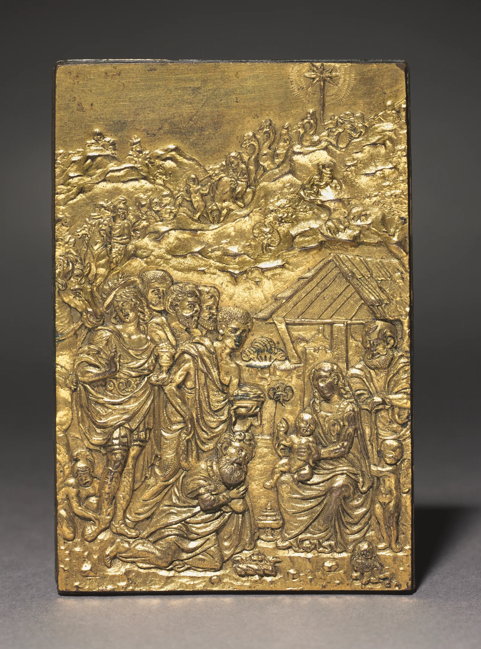 Placa de bronce dorado en relieve, Italia, hacia 1500: la comitiva de los Reyes baja por un paisaje rocoso hacia el establo, con la estrella arriba