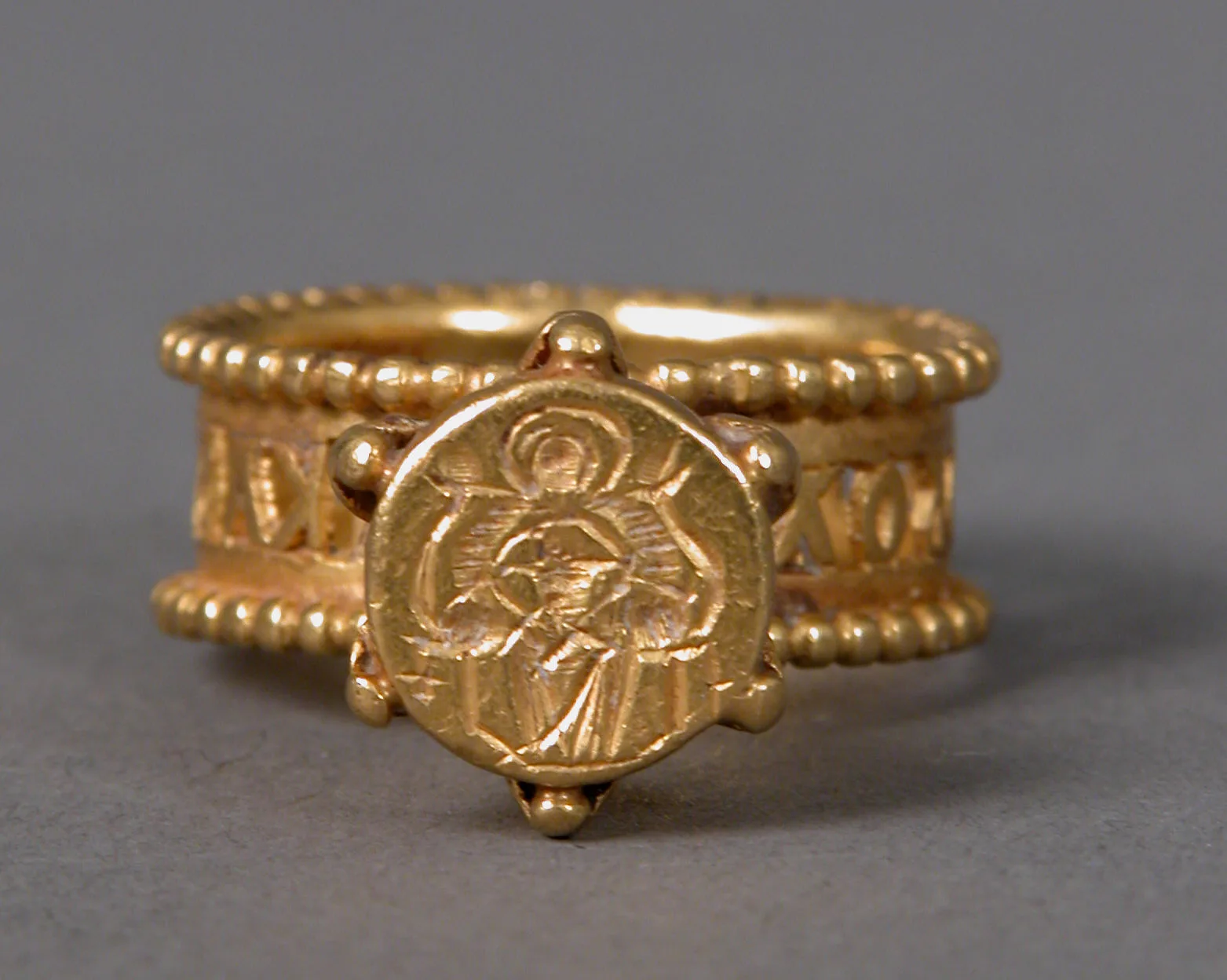 Goldring mit einem Bild auf der runden Platte, umrahmt von Granulation, und einer Inschrift entlang des breiten Reifs