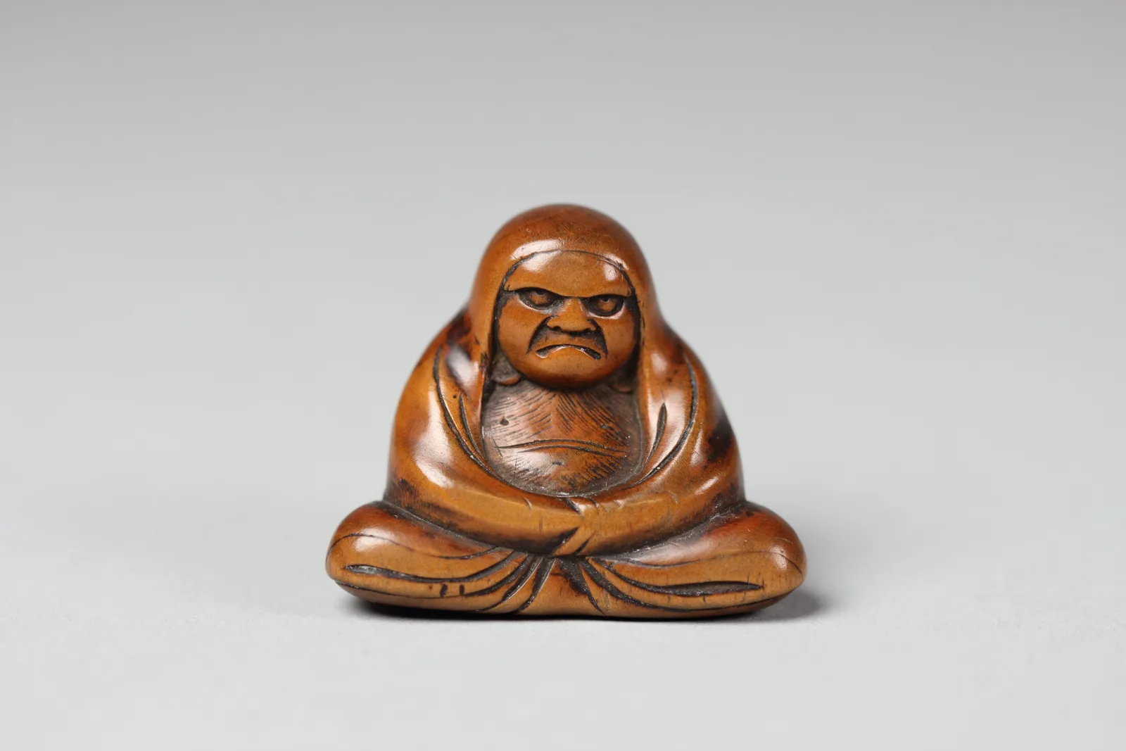 Hölzerne Netsuke in Form einer sitzenden Daruma-Figur